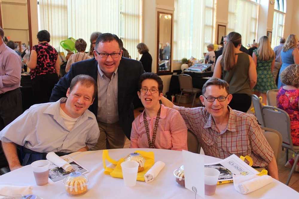 ANCOR Board Member Chad VonAhnen posing at a fundraiser with three of the people supported by his agency, Johnson County Developmental Supports