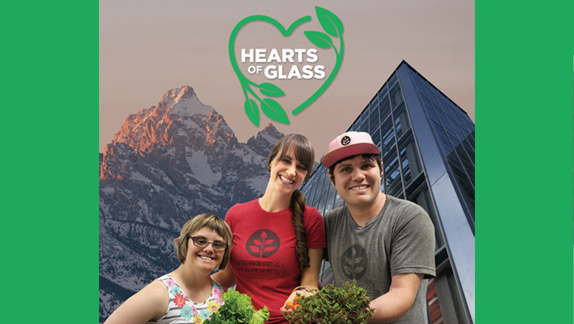 Hearts of Glass image with a green heart around the words 'Hearts of Glass' with an image of three people smiling in front of a tall building and large snow covered mountain.