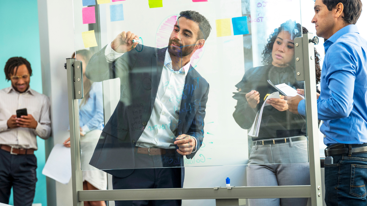 Young professionals collaborating together at a whiteboard using colorful sticky notes.