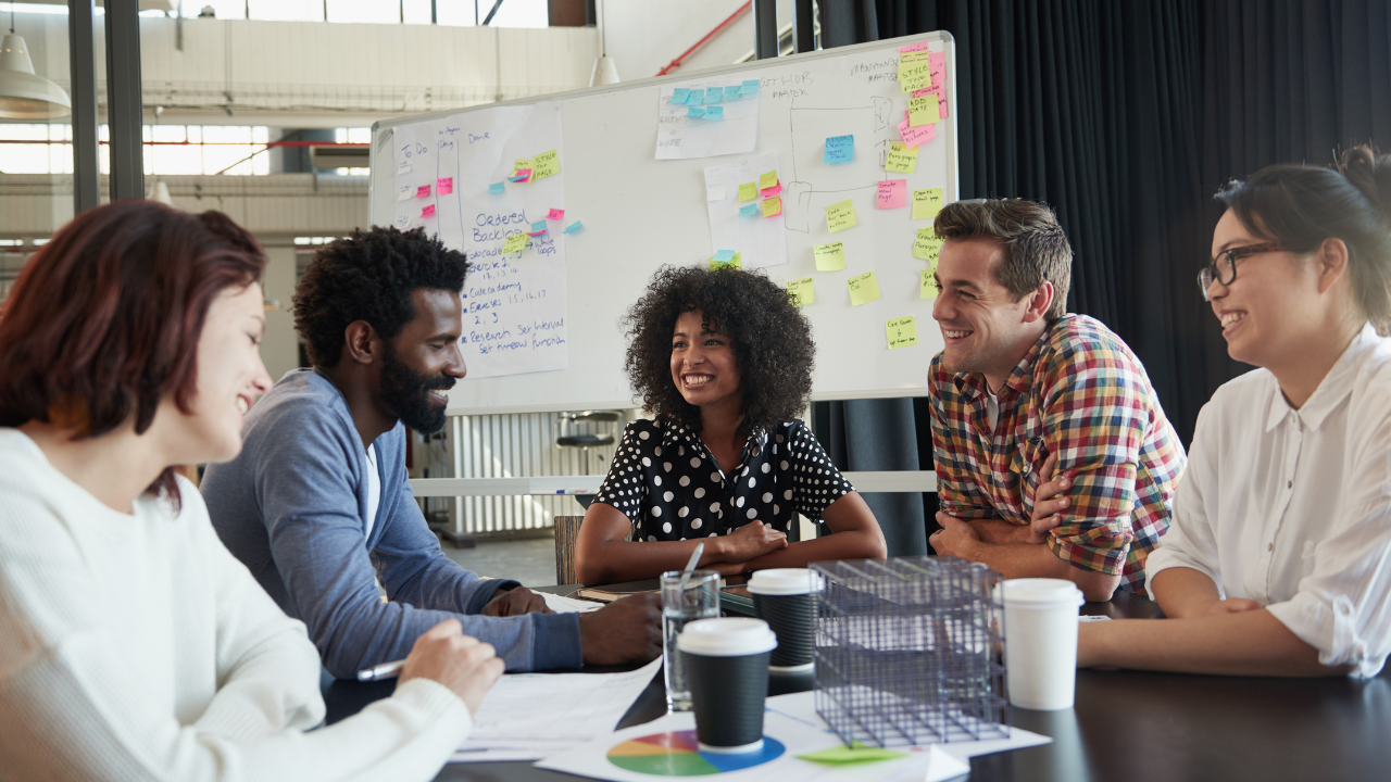A team of five young professionals gathered around a table.