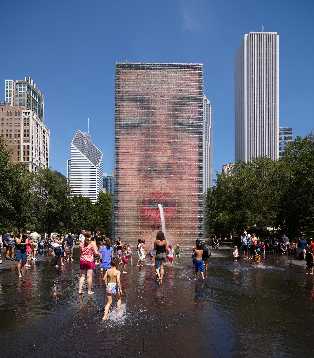 An image of people playing in the water in front of Crown Fountain, an interactive art installation in Chicago.
